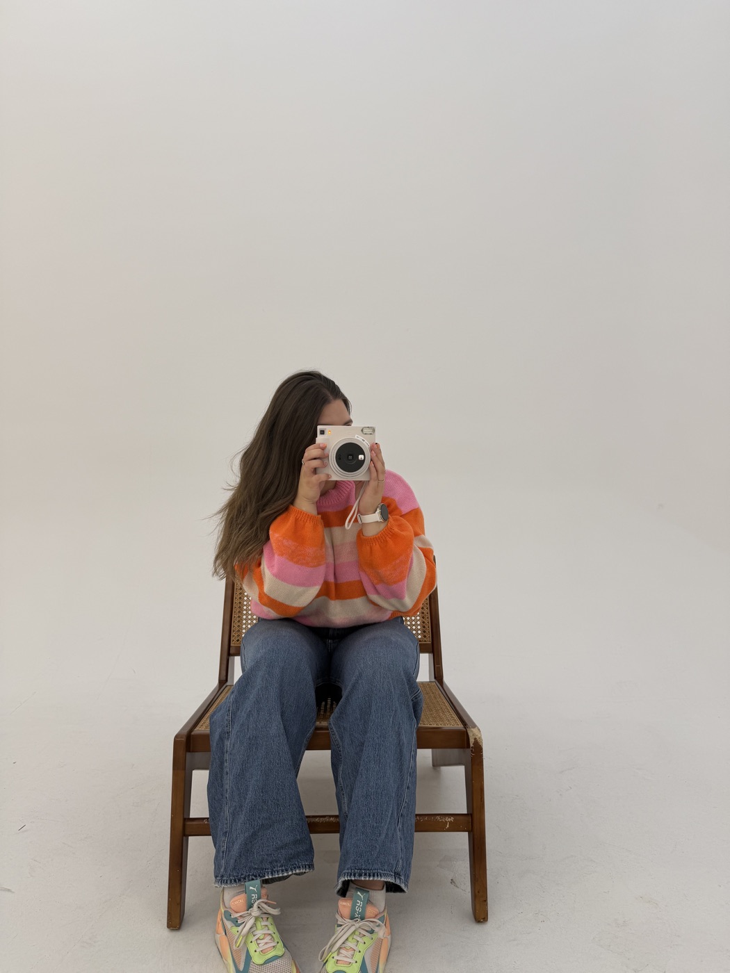 Billie, assise, vise l’objectif d’un appareil Instax