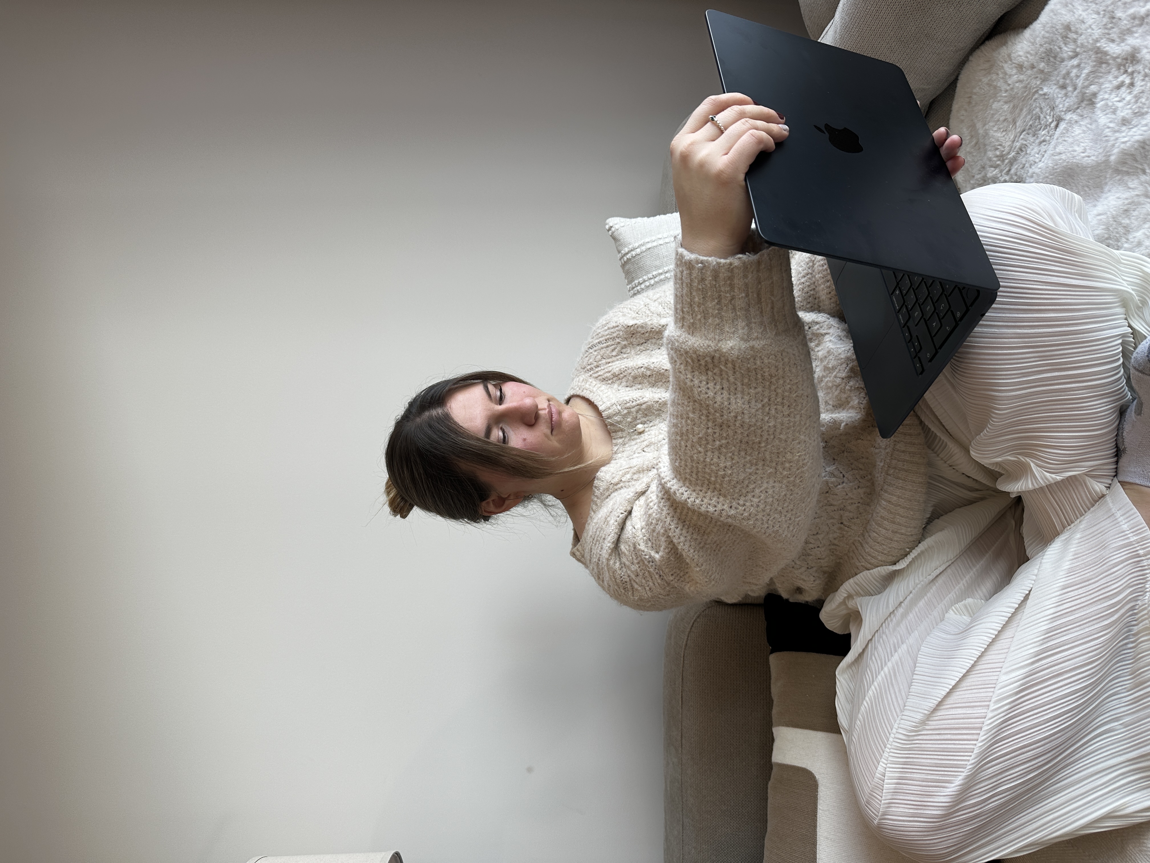 Billie assise en tailleur sur le canapé, concentrée sur son ordinateur
